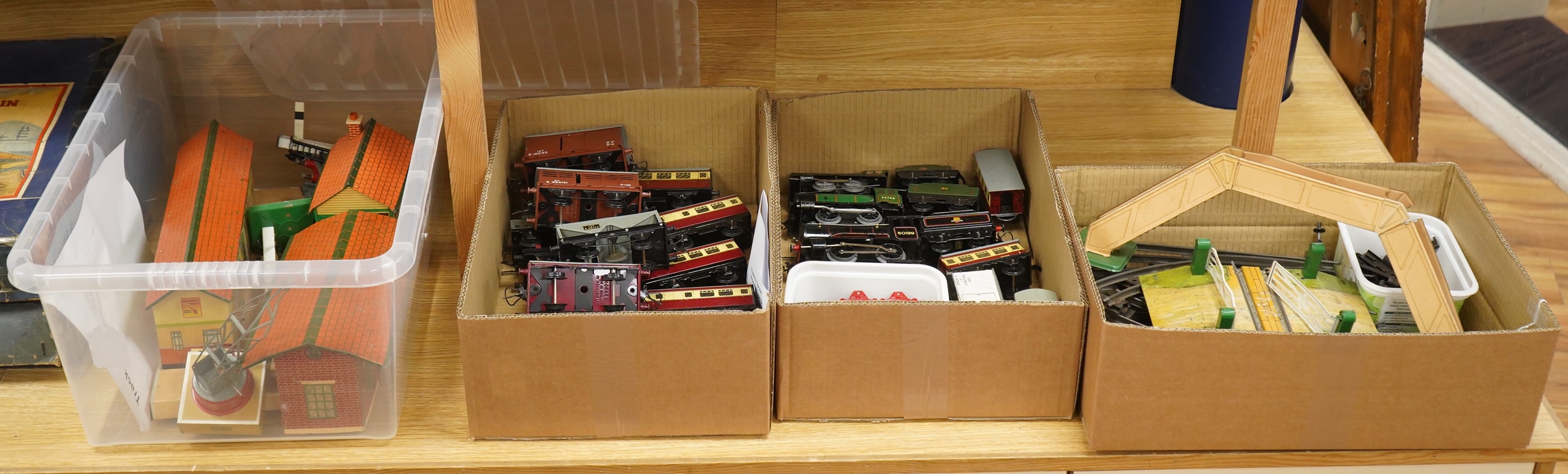 A collection of 0 gauge Hornby tinplate clockwork railway, including four BR locomotives, 17 freight wagons and four wheel coaches, together with a station building, signal cabin, and Goods depot (missing base), plus a f